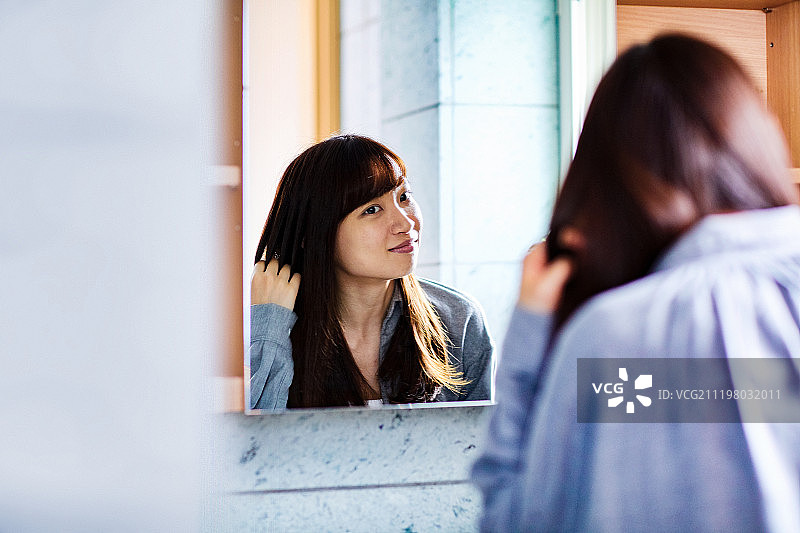 年轻女人在镜子前梳头图片素材