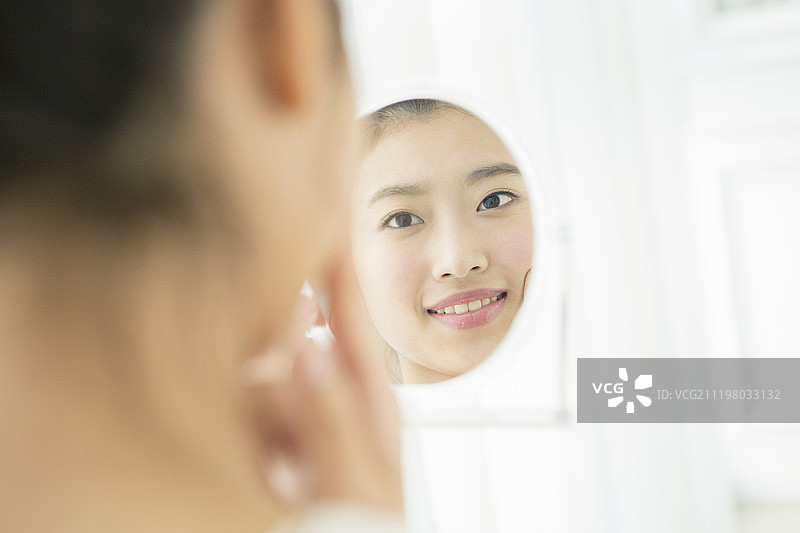 年轻女人在镜子里看自己的脸图片素材