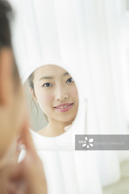 年轻女人在镜子里看自己的脸图片素材