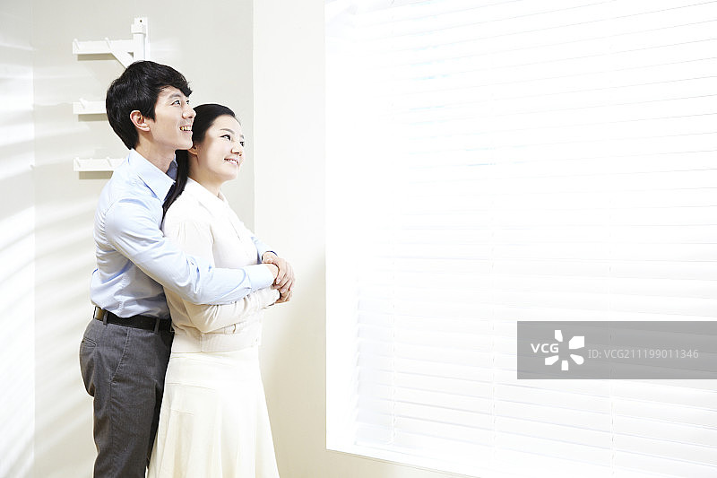 百叶窗旁拥抱的情侣摄影图片素材