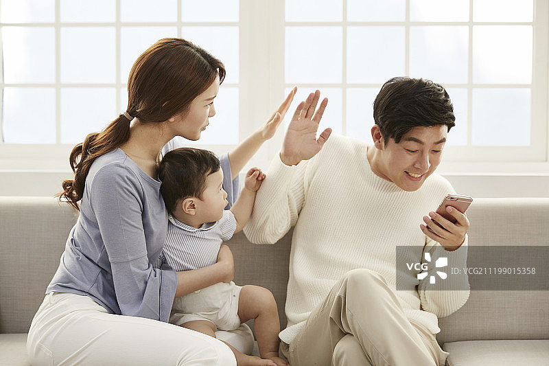 一家人在沙发上看手机，有婴儿图片素材