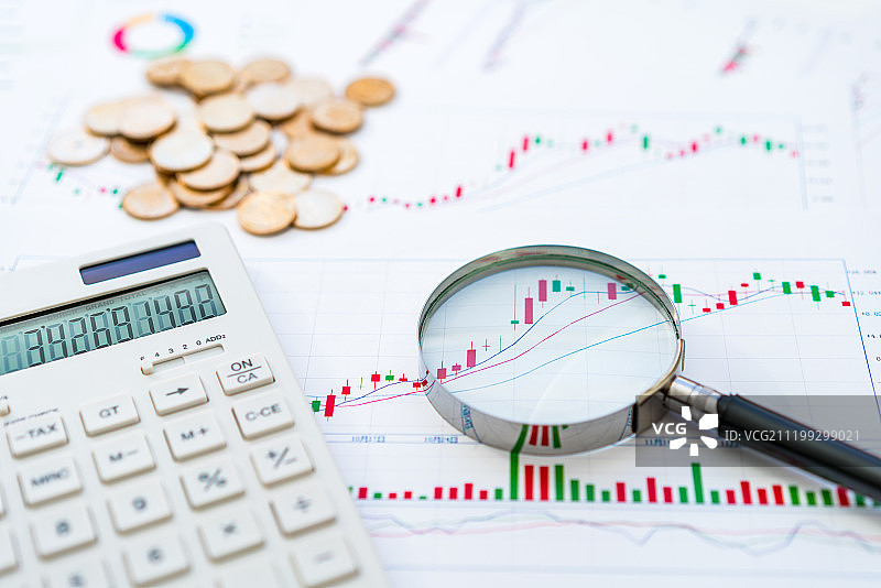 股票k线图背景下的计算器金币放大镜图片素材