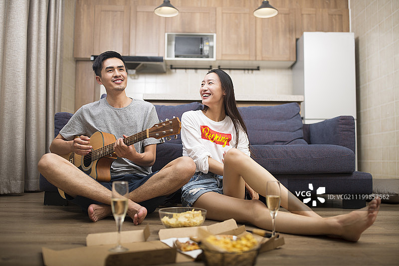 快乐的情侣在客厅演奏吉他图片素材