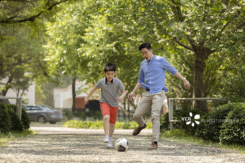快乐的父子在草地踢足球图片素材