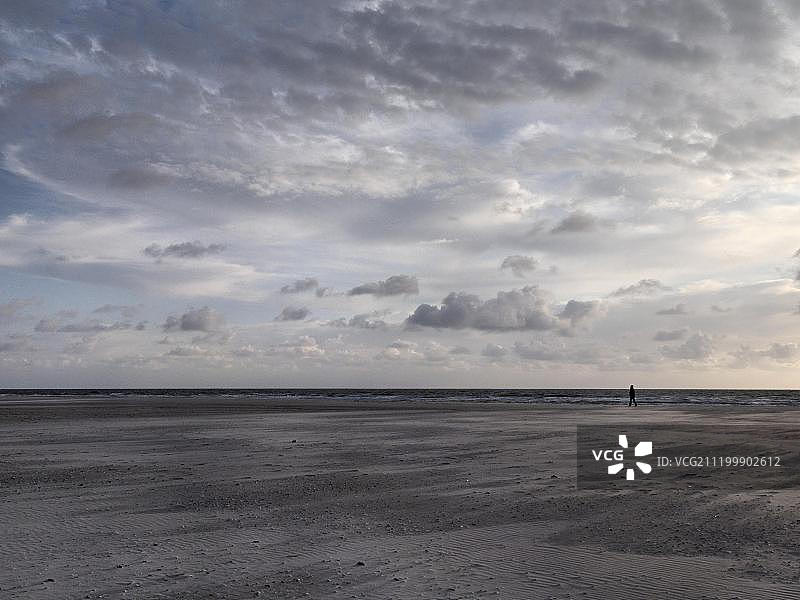 在远处海滩上行走的人，德国石勒苏益格-荷尔斯泰因州阿姆鲁姆岛，欧洲图片素材