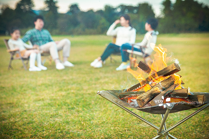 家庭露营：两个孩子和家人在篝火旁享受乐趣图片素材