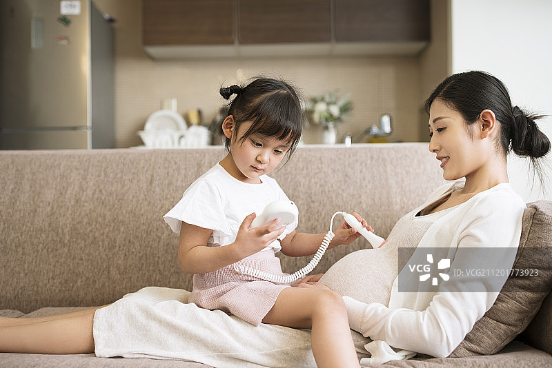 小女孩用胎心仪给怀孕的妈妈做检查图片素材