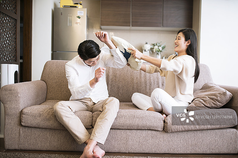年轻情侣在家打枕头仗图片素材