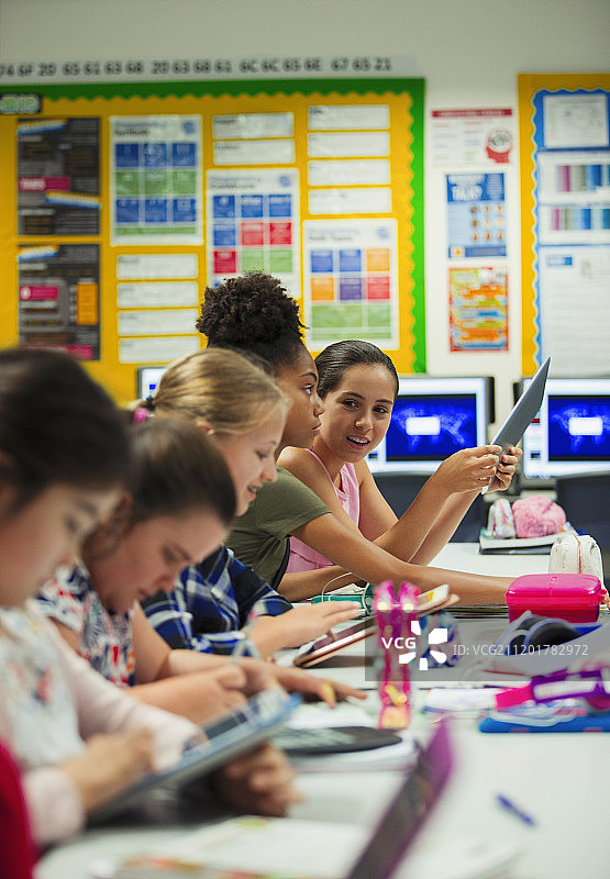 在教室的课桌上使用平板电脑的初中女生图片素材