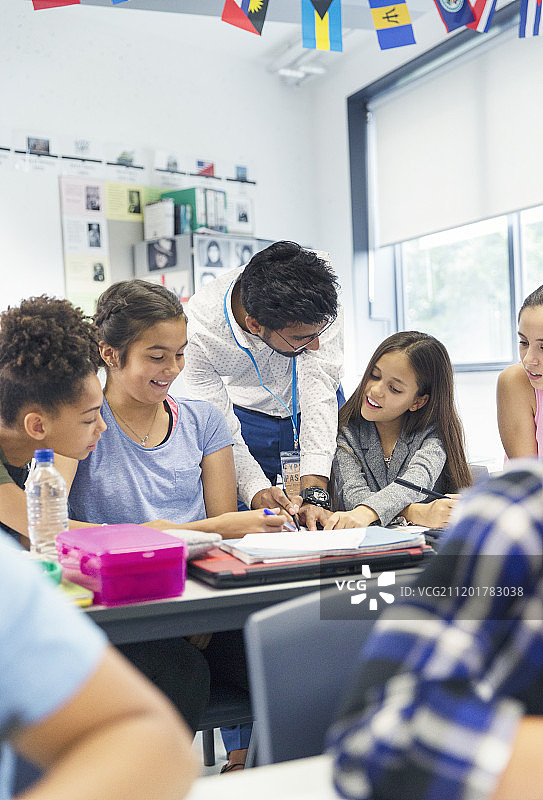 老师在教室的课桌旁辅导初中生图片素材
