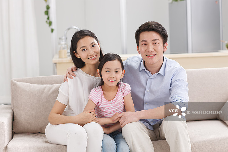 幸福的一家三口坐在客厅的沙发上图片素材