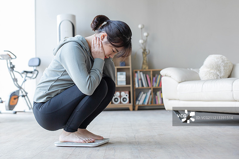 女人在客厅，体重秤，饮食，坐着，焦虑图片素材