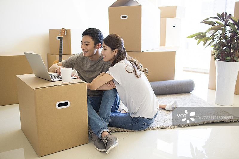 年轻夫妇在新房里使用笔记本电脑图片素材