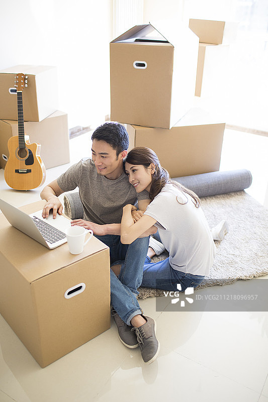 年轻夫妇在新房里使用笔记本电脑图片素材