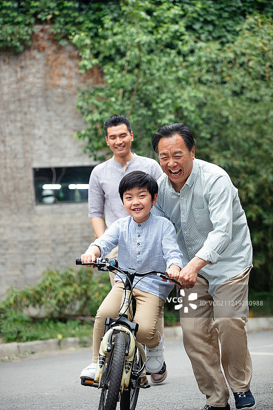 爷爷协助孙子骑自行车图片素材