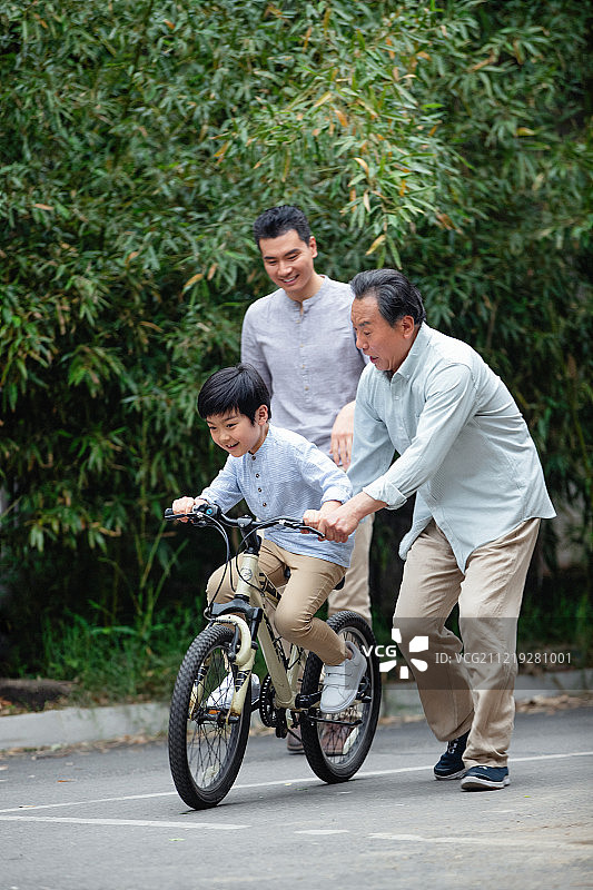 爷爷协助孙子骑自行车图片素材