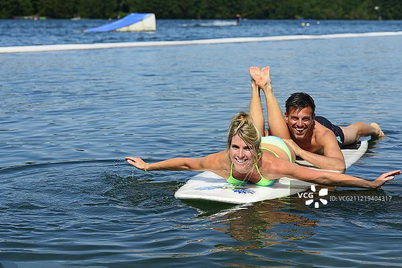 在德国巴伐利亚伊萨尔河畔沃尔特湖上的SUP板上的一对情侣图片素材