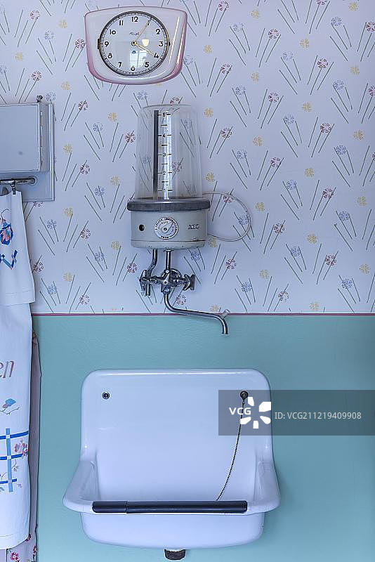 20世纪50年代厨房里的挂钟、热水锅炉和水槽，位于德国巴伐利亚图片素材