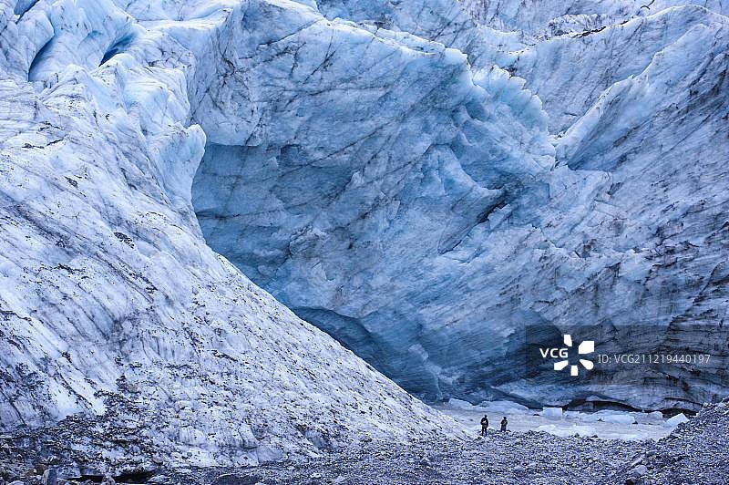 游客徒步前往新西兰南岛福克斯冰川的巨大冰川流出地图片素材