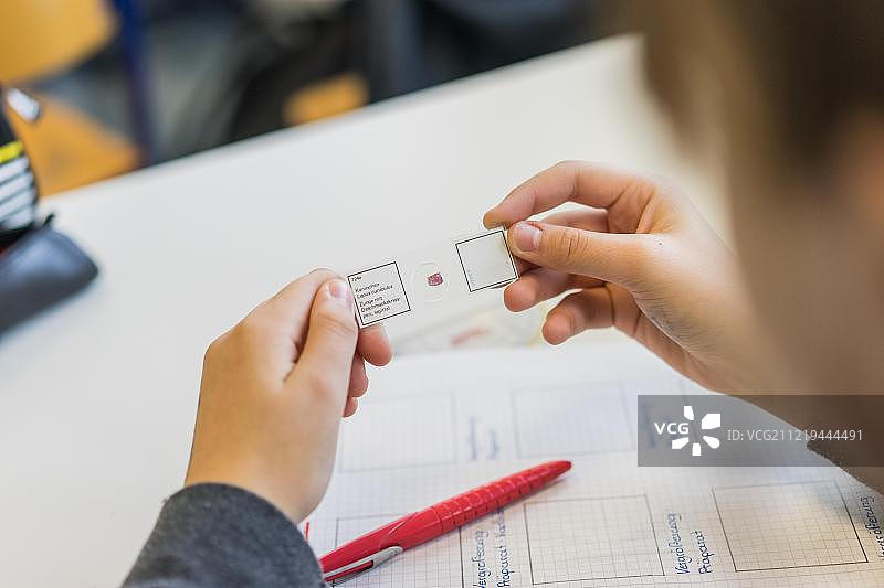 学生手持显微镜样本，在德国黑森州学校上生物课图片素材