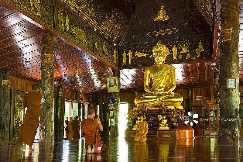 泰国加拉信府卧佛寺金色佛像前的僧侣图片素材