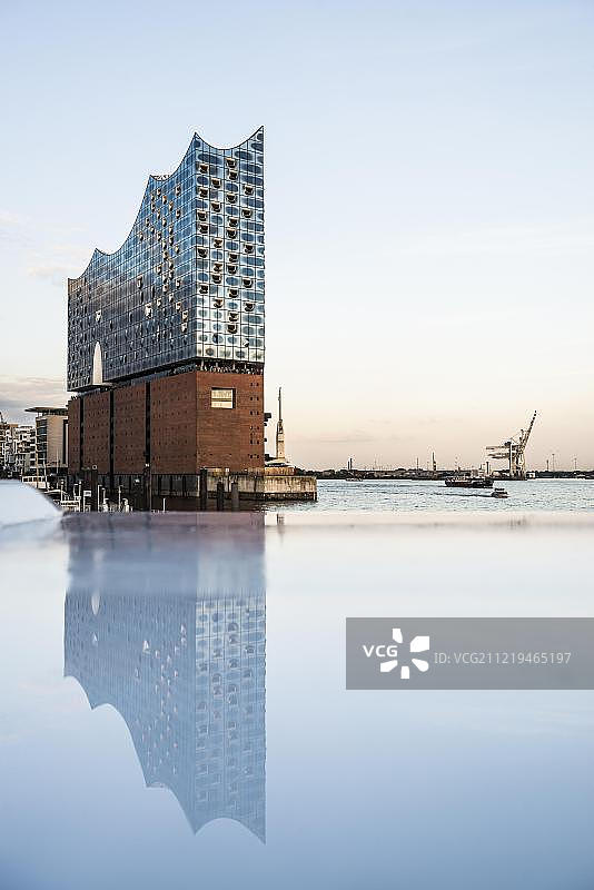 易北爱乐厅，建筑师赫尔佐格和德梅隆，港口新城，德国汉堡，欧洲，在夜晚灯光下与水面倒影交相辉映图片素材