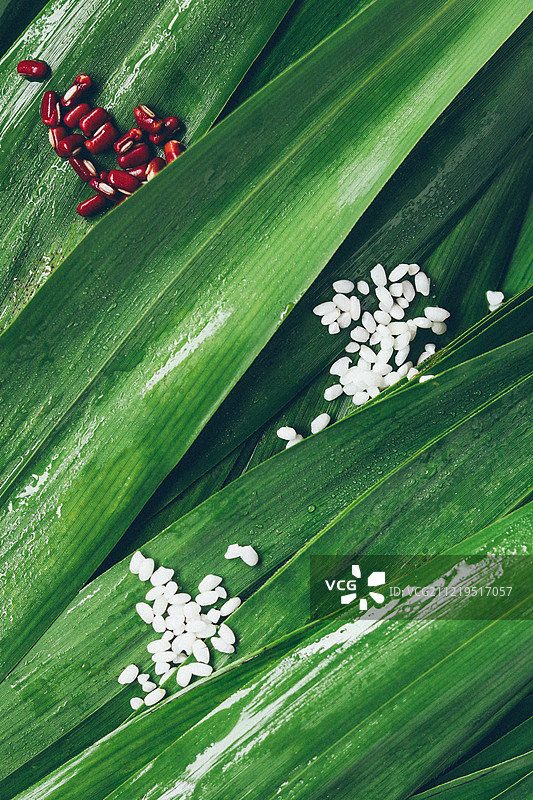 散落在新鲜粽叶上的糯米与红豆图片素材