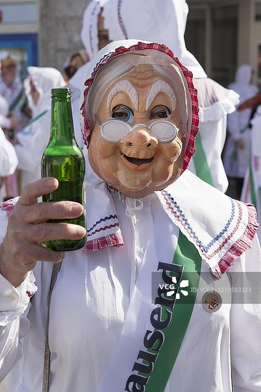 奥斯see狂欢节：戴着面具、穿着白色长袍、手持瓶子的鼓手，奥地利施蒂利亚州巴德奥斯see图片素材
