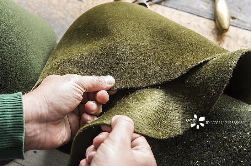 帽子工匠车间：检查不同色调的绿色羊毛毡帽图片素材