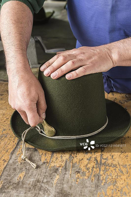 在制帽工坊，使用铁工具收紧羊毛毡帽的成型绳图片素材