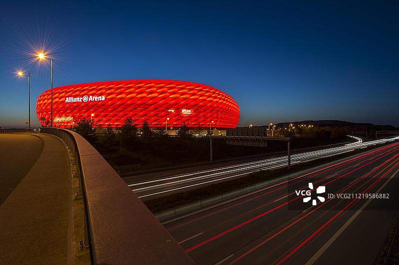 德国慕尼黑安联竞技场夜景：红色灯光与车流光迹图片素材