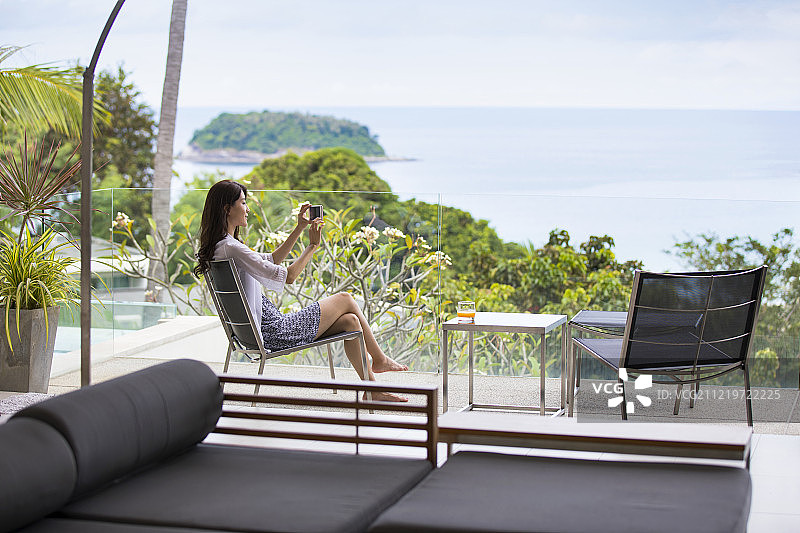 快乐的年轻女子在阳台上拍照图片素材