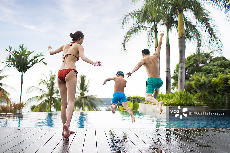 快乐的年轻家庭跳入泳池图片素材
