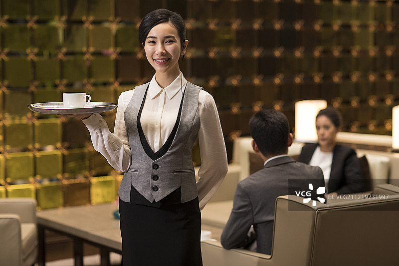 自信的年轻服务员端着咖啡图片素材