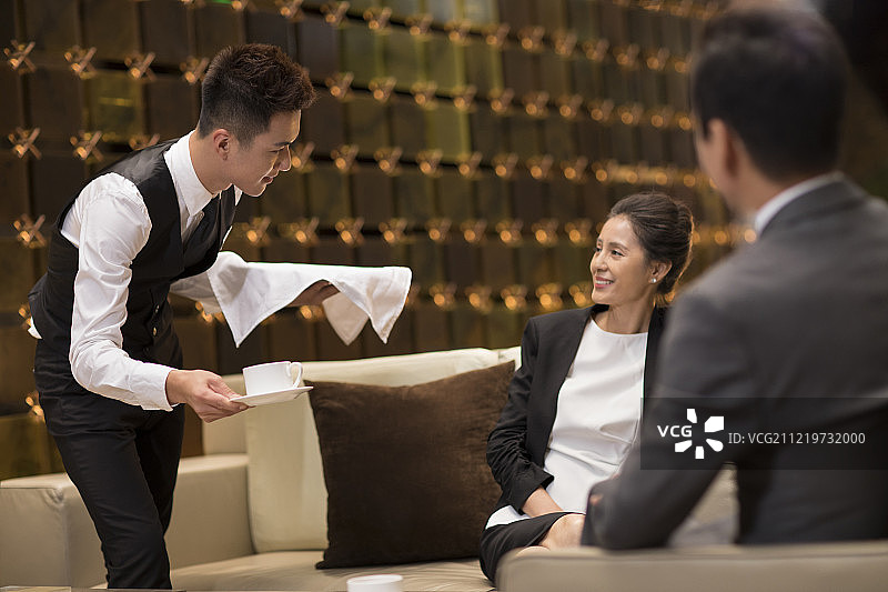 年轻服务员给顾客端咖啡图片素材