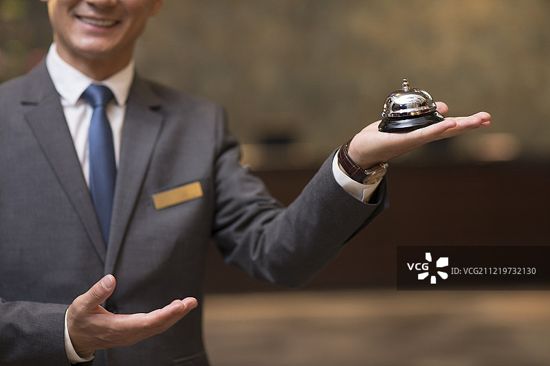 自信的酒店经理拿着服务铃图片素材