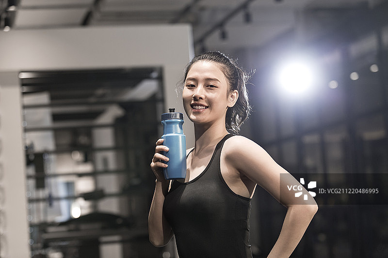 青年女子在健身房手里拿着水杯图片素材