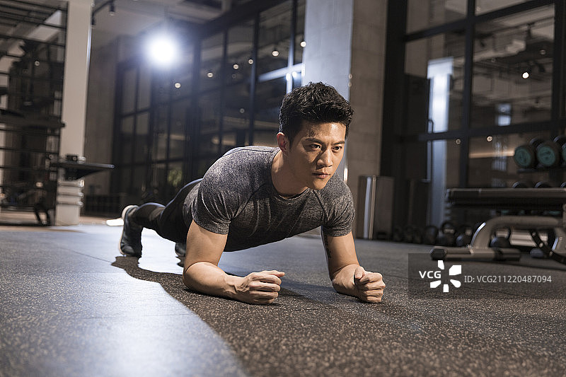 年轻男子在健身房做平板支撑运动图片素材