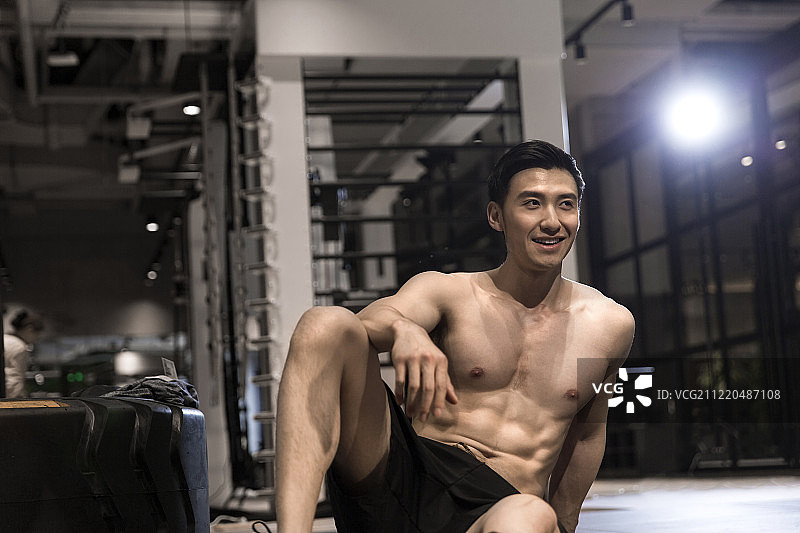 青年男子在健身房坐在地上休息图片素材