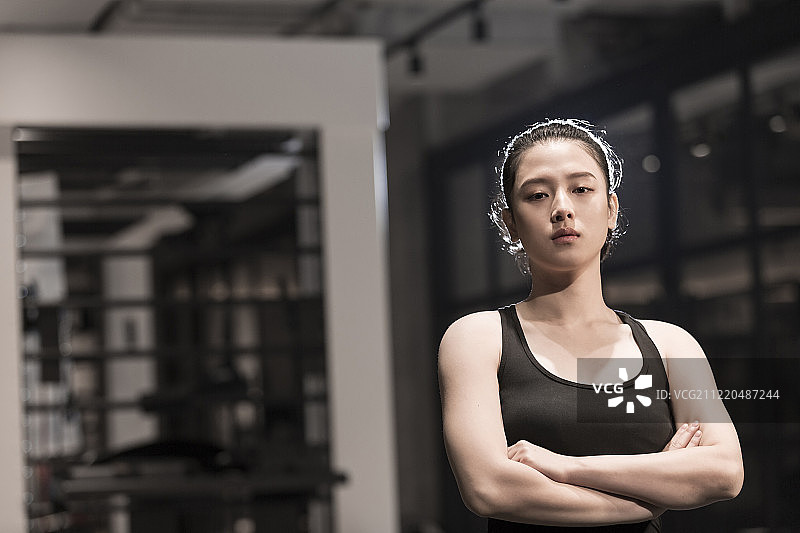 青年女子在健身房注视镜头双臂交叉肖像图片素材