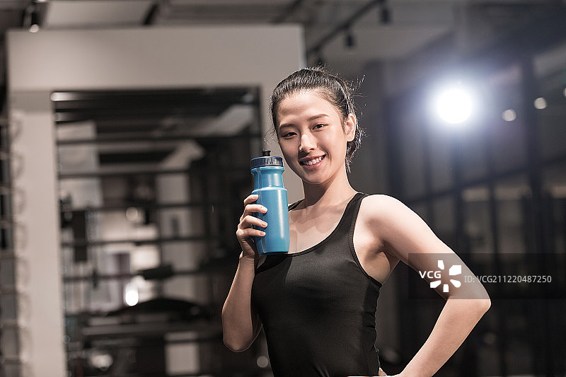 青年女子健身后叉腰展示水瓶图片素材