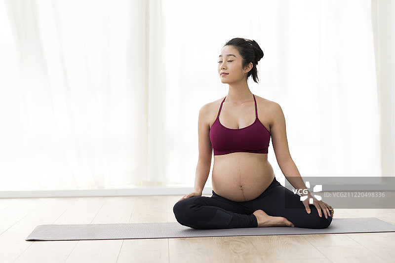 年轻孕妇在家练习瑜伽图片素材