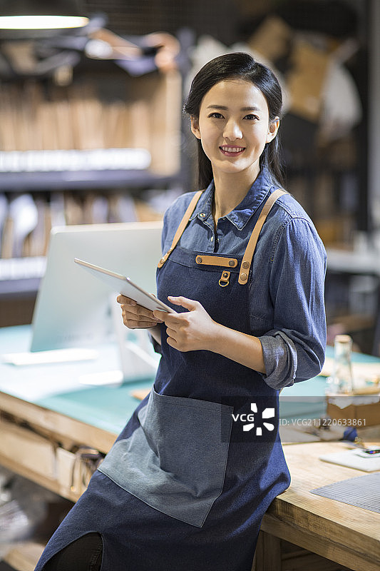 自信的手工皮具匠人拿着平板电脑图片素材