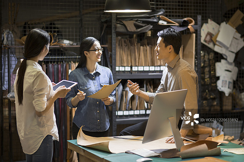 手工皮具匠人团队在工作室里讨论图片素材