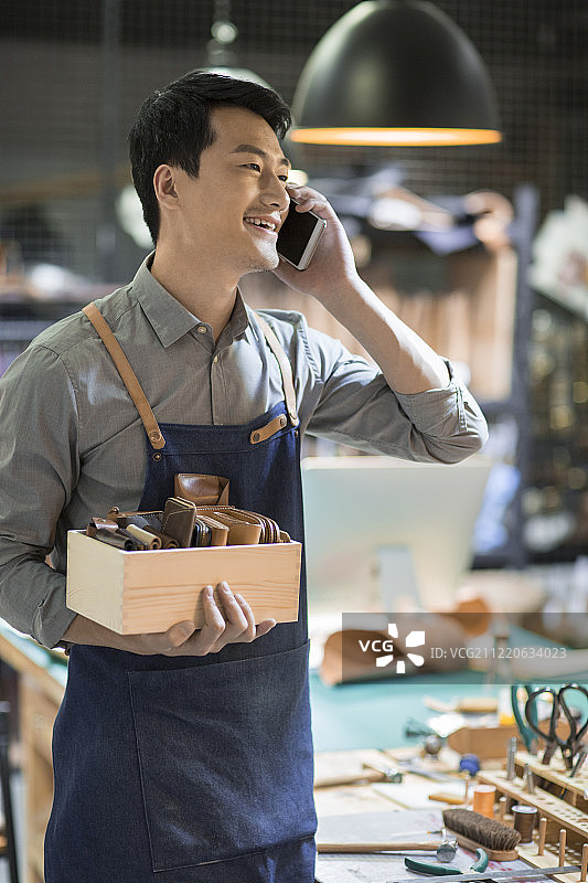 手工皮具匠人在工作室里打电话图片素材