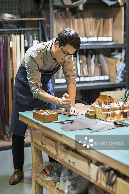 手工皮具匠人在工作室里工作图片素材