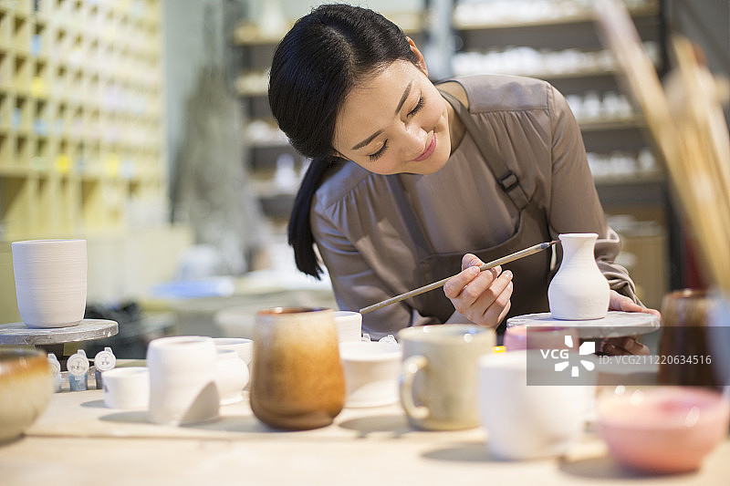 年轻陶艺师给陶胚上色图片素材