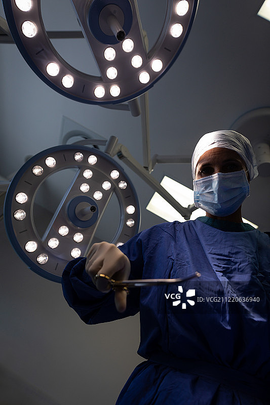 诊所里一位年长的白人女外科医生手持手术剪刀的低角度视图图片素材