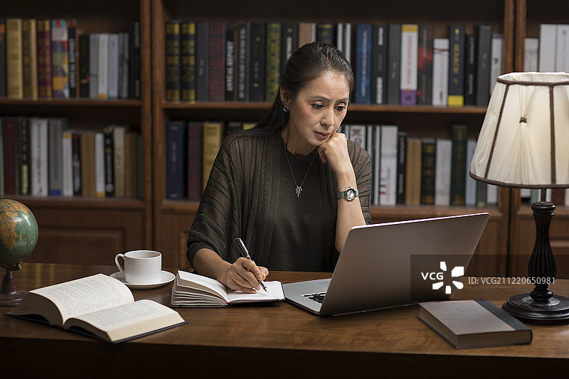 优雅的中年女士在书房使用笔记本电脑图片素材