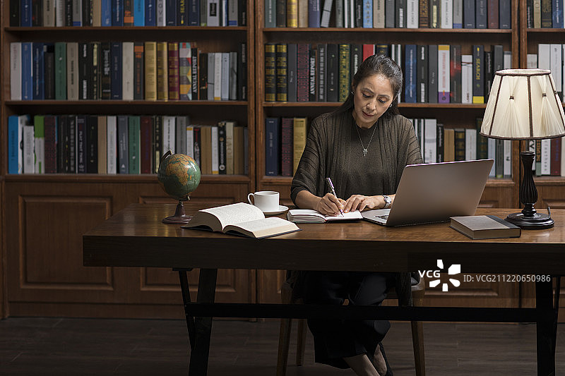 优雅的中年女士在书房使用笔记本电脑图片素材